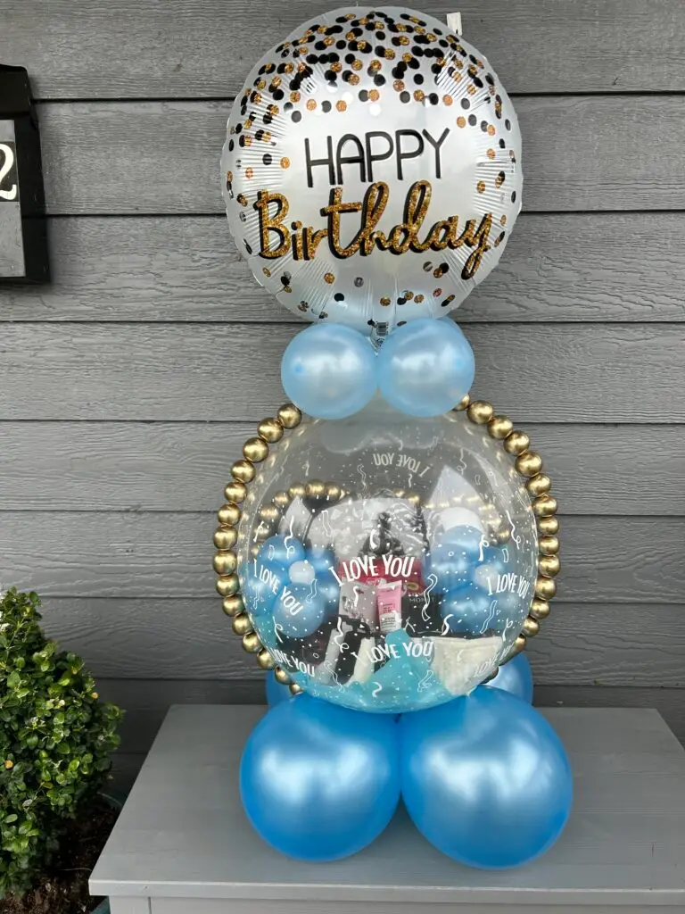 Stuffed balloon gift with gold and blue mini balloons inside a clear balloon for a birthday celebration.